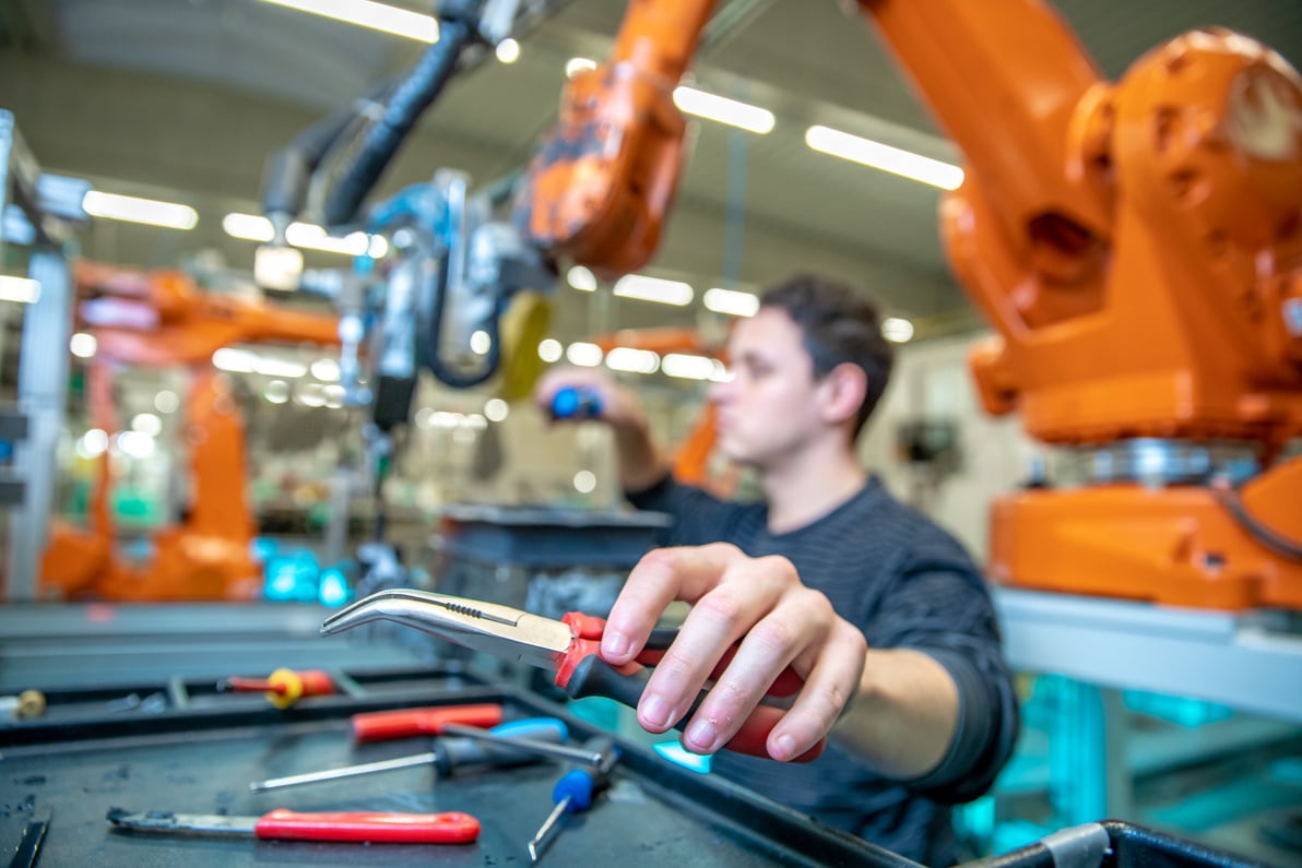 Technician Repairing a Robotic Arm in a Factory