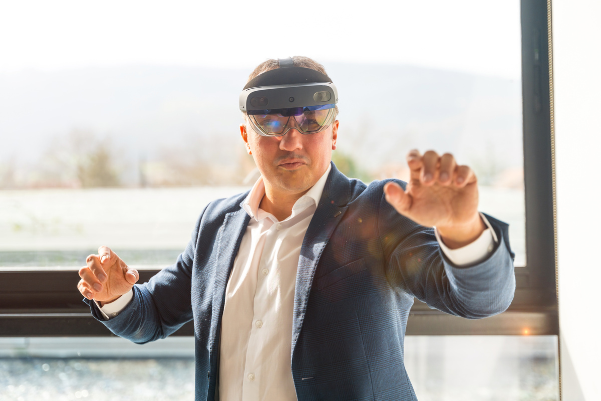 Businessman wearing mixed reality goggles touching interactive screen